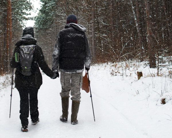 两个人在白雪皑皑的树林里徒步
