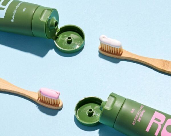 浅蓝色背景的绿色牙膏管和竹牙刷
