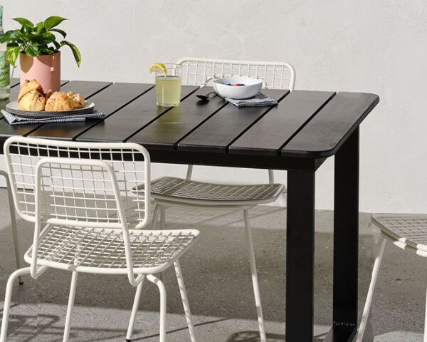 一张黑色的户外桌子，上面放着盘子和植物。