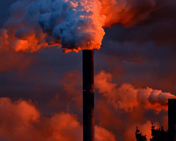 蓝色和红色的天空映衬着从一家公司的高高的烟囱里冒出的烟羽