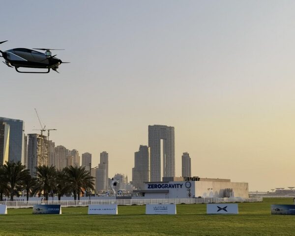 日落时分，一辆电动飞车飞过迪拜的一片田野，背景是摩天轮